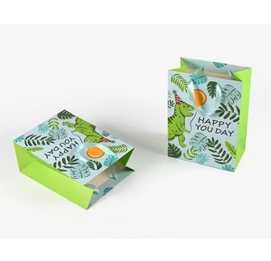 Detailed view of green cartoon dinosaur gift bag with ribbon handles and happy you day text