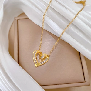 Detail of gold heart pendant necklace featuring square cubic zirconia on silk fabric