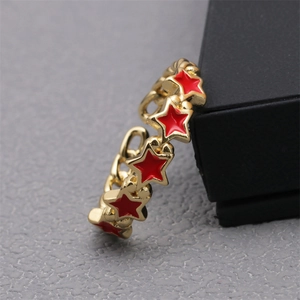 Detail of 18K gold star ring featuring red enamel pentagrams and chain texture band