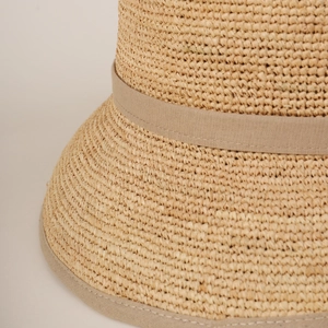 Close-up of fine raffia straw weaving and elegant light brown ribbon trim on a sun hat