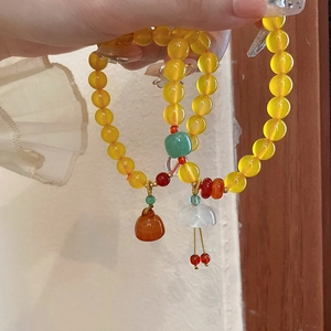 Details von gelben Perlenarmbändern mit Blumenanhängern und Quasten im Retro-China-Stil