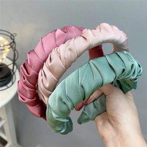 Detailed view of pleated satin headbands in pink, champagne, and green colors