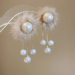 Detail showing plush fur texture and elegant pearl tassels on gold earrings