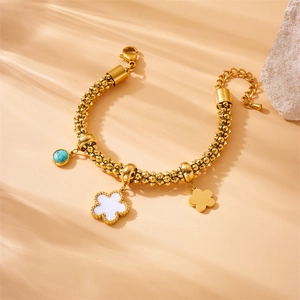 Gold stainless steel chain bracelet with blue marble bead and flower charms on warm fabric