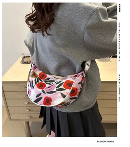 Floral print crescent crossbody bag with adjustable white strap on a model outfit