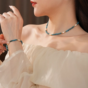 Detail of necklace and bracelet set with blue beads, pearls and gold accents on model