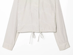 Detail of checkered nylon jacket showing drawstring hem and woven fabric texture