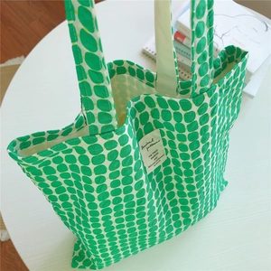 Close-up of green checkered canvas tote bag with woven strap and interior lining