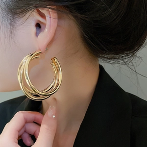Close-up of gold multi-layered hoop earrings showing metallic luster on a female model