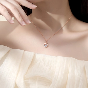 Elegant rose gold heart pendant necklace with crown design on model neck collarbone