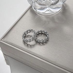 Close-up of silver Cuban link rings with micro-pave crystals on a metal display box