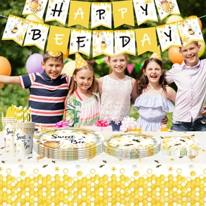 Outdoor birthday scene showing bee-themed party tableware set and happy bee day banner