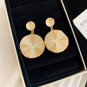 Detailed close-up of golden vintage round earrings with spiral texture on black velvet