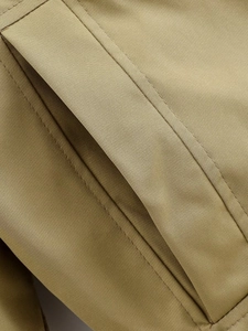 Détail de la poche de parka kaki avec texture tissée dense et coutures renforcées de qualité