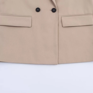 Detailed close-up of khaki blazer featuring double-breasted buttons and flap pocket design