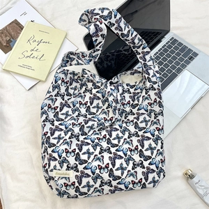 Lifestyle shot of a butterfly print tote bag next to a laptop and books for daily commute