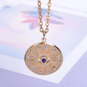 Detailed close-up of gold eye pendant necklace with blue stone and sparkling rhinestones
