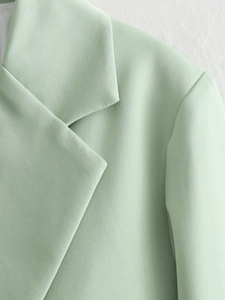 Detailed close-up of light mint green blazer fabric texture and professional lapel stitching