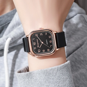 Detail showing square rose gold watch case with black textured dial and Arabic numerals