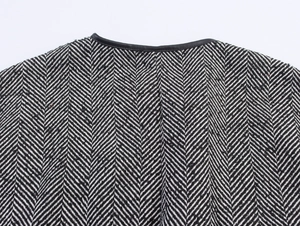 Detail of black and white herringbone tweed fabric with black leather collar trim
