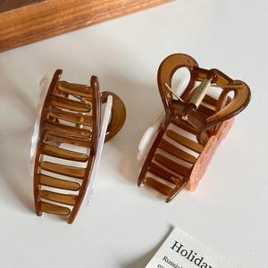 Two-piece coffee acrylic hair claws set with sleek gold springs on a clean background