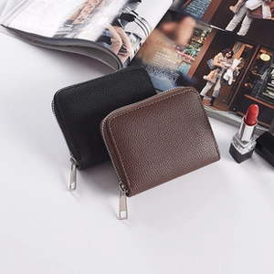 Detail showing black and brown pebble leather mini wallets with silver zippers on a magazine