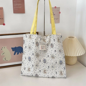 Detail of canvas tote bag featuring teddy bear print and contrasting yellow handles