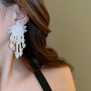 Detail of white frosted flower petals and long pearl tassel earrings on model