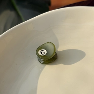 Detailed close-up of a mini green acetate hair claw with number 6 in a ceramic bowl