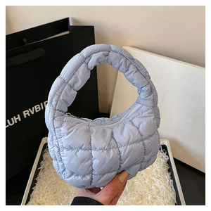 Close-up of light blue quilted cloud bag showing soft padded texture and puffy handle