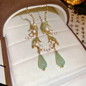 Elegant lily of the valley earrings with green teardrop pendants on dark jewelry box