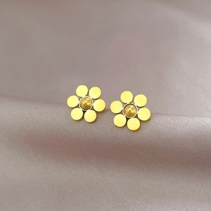 Macro shot of gold six-petal flower stud earrings made of titanium steel on silk