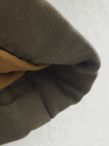 Macro view of dark grey canvas texture with mustard yellow lining on a loose jacket
