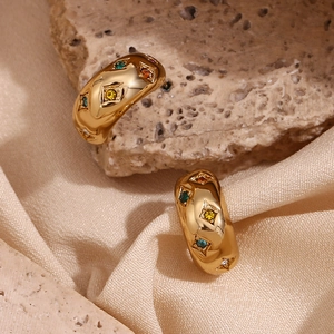 Detail of 18K gold-plated hoops featuring colorful star-set zircons on silk fabric