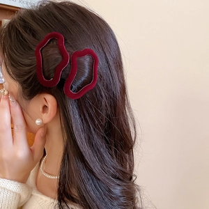 Detail of red velvet geometric hair clips showing the soft texture and curved design