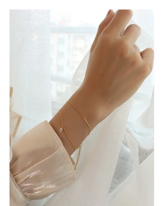 Close-up of a double-layer gold titanium bracelet with a sparkling zircon stone charm