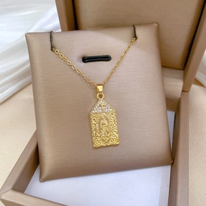Gold Virgin Mary pendant necklace with sparkling rhinestones on a jewelry cushion