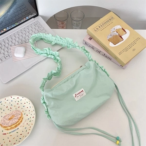 Macro shot of mint green pleated nylon cloud bag on a desk with a white fabric label