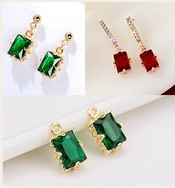 Close-up of emerald and ruby rectangular cut charms with gold-plated metal bases