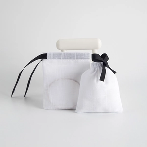 Close-up of white cotton jewelry pouches with black drawstring for gift packaging