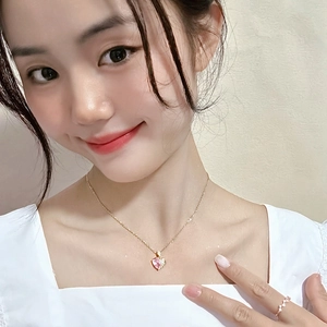 Gros plan d'un collier doré avec pendentif cœur rose et bague assortie sur mannequin