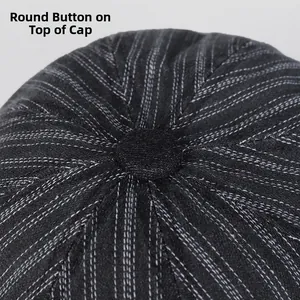 Gros plan du bouton central sur béret rayé foncé avec coutures contrastées blanches