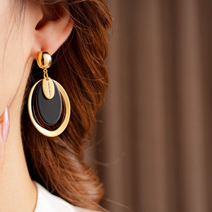 Detail of gold oval earring with black resin inlay and Hand Made engraving on model