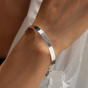 Close-up of a minimalist silver metal cuff bracelet with high-polish mirror finish