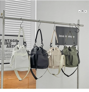 Detail of nylon drawstring bucket bags in white, black, beige and olive green colors