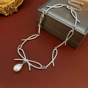 Vue détaillée du collier nœud argenté orné de strass et d'un pendentif en perle