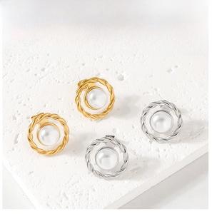 Macro shot of twisted metal rope frame earrings with large white pearls in gold and silver