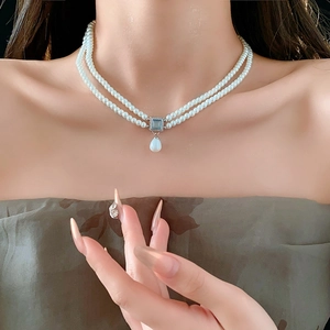 Detail of double-layer pearl necklace featuring a blue square stone and waterdrop pendant
