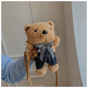 Detail of cute brown plush bear crossbody bag wearing blue denim overalls and plaid bow