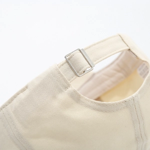 Detailed view of the adjustable metal buckle and cotton twill strap on the beige baseball cap